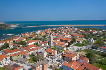 Naklejka na ściany i meble Aerial view of city of Nin. Summer time in Dalmatia region of Croatia. Coastline and turquoise water and blue sky with clouds. Photo made by drone from above.