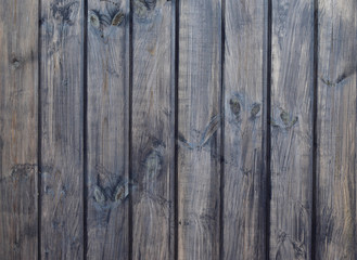 The ordered texture of the house wall from dark-stained wooden planks close-up