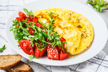 Classic omelet with cheese and tomatoes salad on white plate.