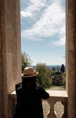 Traveler girl with Vintage Straw hat looking monumets and one of the XIVchapel along the path of the historic pilgrimage route from Sacred Mount or Sacro Monte of Varese, Italy