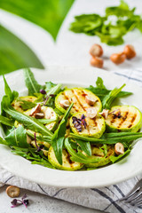 Grilled zucchini salad with arugula and nuts in white plate. Healthy vegan food concept.