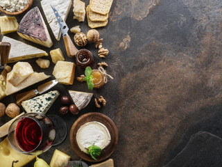 Cheese platter with organic cheeses, fruits, nuts and wine on stone background. Top view. Tasty cheese starter.