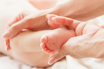 Hands of woman and baby feet, soft focus background