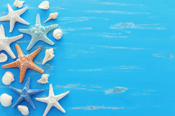 Fototapeta na wymiar vacation and summer concept with starfish and seashells over blue wooden background. Top view flat lay