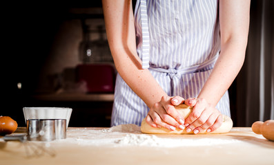 Obraz na płótnie Canvas Woman's hands knead dough on a table