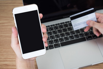 People sitting in the room using a smartphone, paying via a credit card on a wooden table. Black screen.