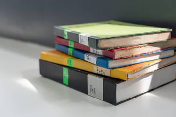 Books stacked on the table in library at university in selective focus.