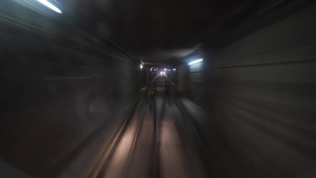 Front view from funicular cabin running inside dark tunnel, passing loop, travelling up. POV time lapse shot, walls of underground passage seen in motion blur