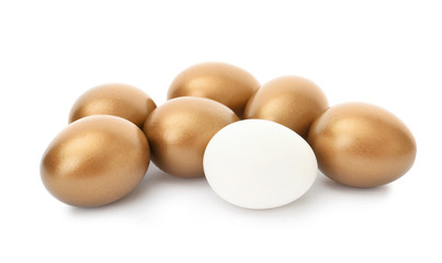 Ordinary egg among golden ones on white background