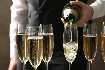 Waiter pouring champagne into glass, closeup view