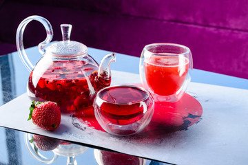 red tea with strawberries in a glass teapot in a cafe