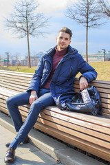 Obraz premium A young guy is sitting on a park bench
