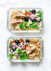 Greek chicken grain lunch box. Lemon herbs chicken, couscous, vegetables, olives, feta cheese lunch box on light background, top view. Mediterranean food concept
