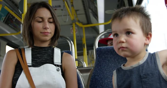 Young mother watching son as they ride the pubic city bus