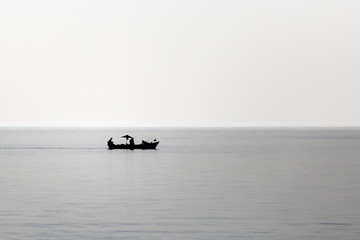 Small fishing boat sails on flat sea in the early morning. Assos, Canakkale / Turkey