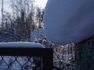 snow lies on a metal fence on a clear day