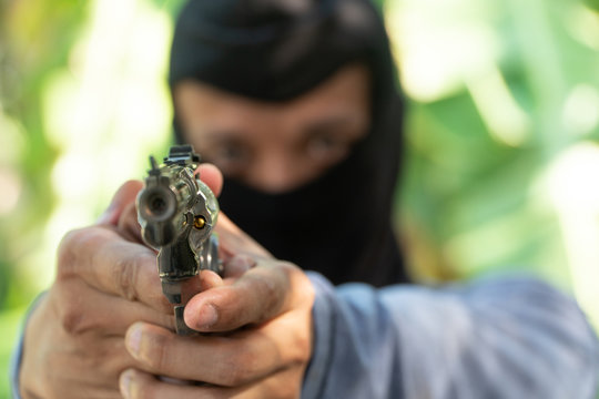 Select Focus Of Gun. Robber In Black Ski Mask Aims With Gun