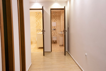 Two open doors to big modern bathroom and toilet. Home interior