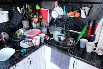 Dirty dishes in the kitchen sink and on the countertop. Not done household chores in the kitchen. A...