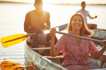Laughing young woman canoeing with friends in the summer