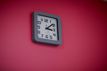 Square wall clock on a bright crimson wall