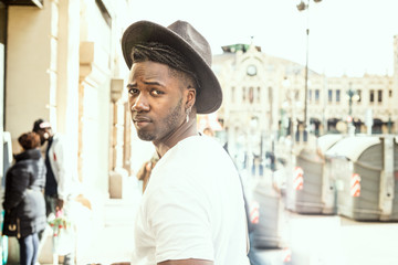 Guy with hat dressed in style and modern in the city. African american guy
