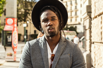 Guy with hat dressed in style and modern in the city. African american guy