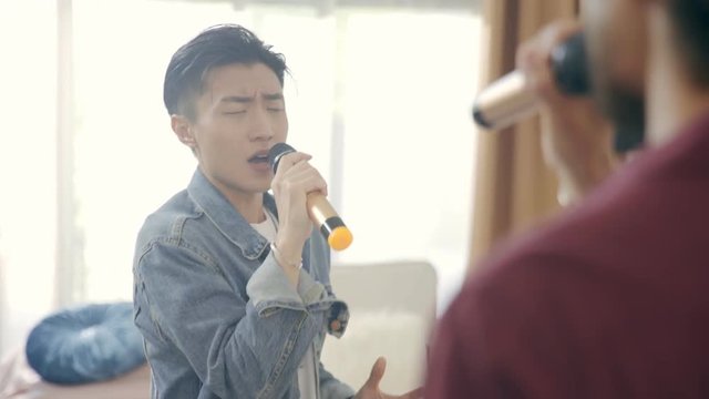 asian singers rehearsing singing song using microphone