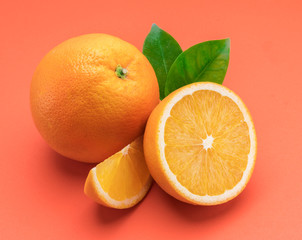 Orange fruit with orange slices and leaves isolated on orange background.