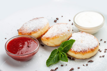 Cottage cheese pancakes with sour cream and jam on white background