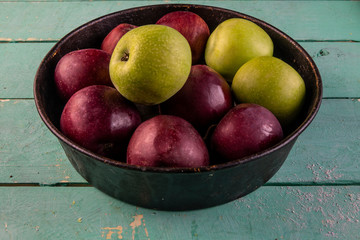Apples in an vintage iron plate on a wooden background. Side view