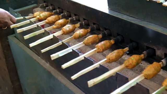 Vendor cooking spicy Jang Lon on charcoal grill machine. Traditional Thai street food for sale in Bang Namphueng Floating Market. Bang Krachao, Thailand.