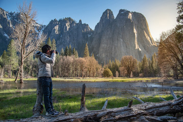 Asian man photographer and tourist holding DSLR camera taking photo of Cathedral Rock landscape in...