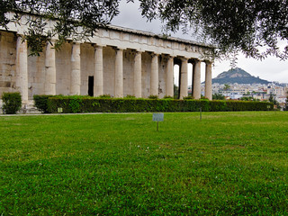 Temple of Hephaestus in Athens, Greece. Grass in the foreground with label "Do not walk on the grass". Lycabettus hill and city building in the background.