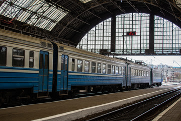 Fototapeta na wymiar Blue cars of an electric train stopping under the roof of a covered apron of the railway station