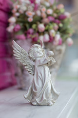 Angle statuette on the background of crimson flowers