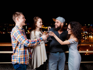 friends with smiles on their faces in the bar have fun, drink cocktails, clink glasses.