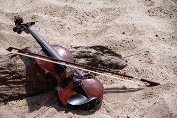 The wooden violin ahd bow put beside timber board,on the beach,blurry light around © Watcharin
