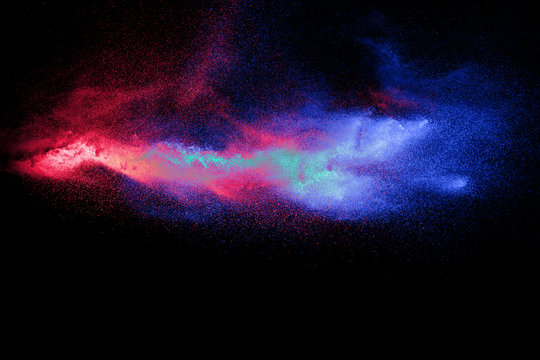 Color powder explosion cloud on black background. Freeze motion of color dust  particles splashing.