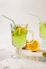 Refreshing lemonade from kiwi and lemon on a light background. Vertical orientation