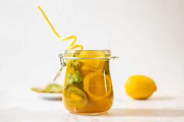 Freshly squeezed orange juice with pulp, kiwi and lemon on a light background. Horizontal orientation