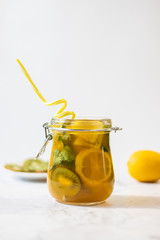 Freshly squeezed orange juice with pulp, kiwi and lemon on a light background. Vertical orientation