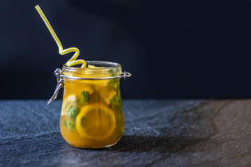 Freshly squeezed orange juice with pulp, kiwi and lemon on a dark background. Horizontal orientation
