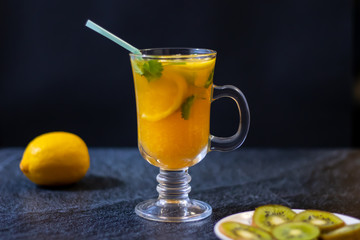 Freshly squeezed orange juice with pulp, kiwi and lemon on a dark background. Horizontal orientation