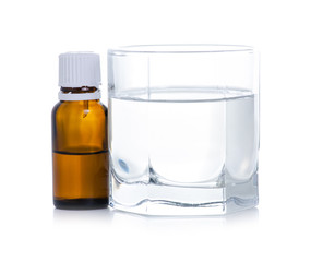 the medicine bottle drips into a glass of water on white background isolation