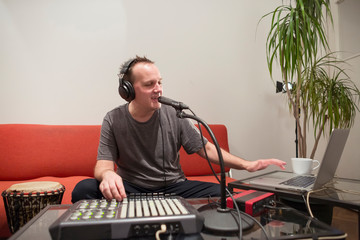 Musician playing midi keyboard in home music studio.