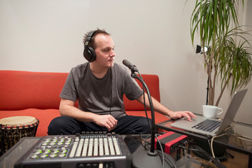 Musician playing midi keyboard in home music studio.