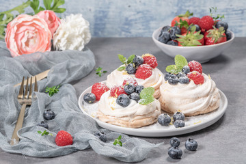 Mini pavlova cakes with fresh raspberries and blueberries.