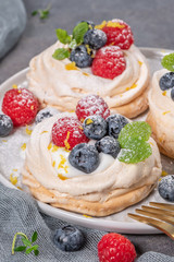 Mini pavlova cakes with fresh raspberries and blueberries.