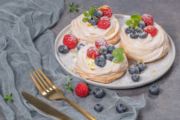 Mini pavlova cakes with fresh raspberries and blueberries.